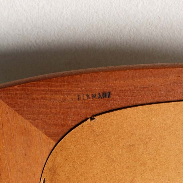 Close-up of vintage teak frame corner with smooth wood grain and "DENMARK" stamp, mid-century British-Danish design.