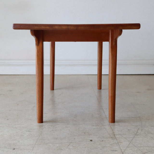 Vintage mid-century British teak coffee table with clean lines, smooth wood grain, and slender tapered legs.