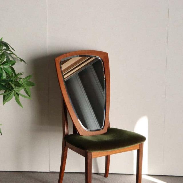 Mid-century vintage teak wall mirror with organic pebble shape, Danish design, rich wood grain, mounted above green velvet.