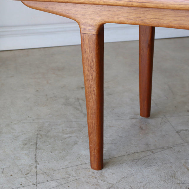 Vintage teak coffee table leg with smooth tapered cylindrical shape and visible wood grain in mid-century British-Denmark.
