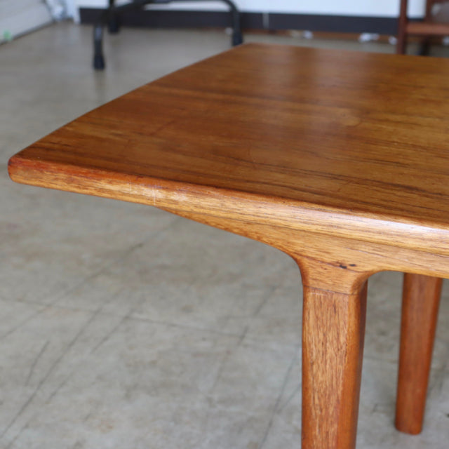 Mid-century British teak coffee table with smooth wood grain and rounded edges, Danish vintage style legs visible.