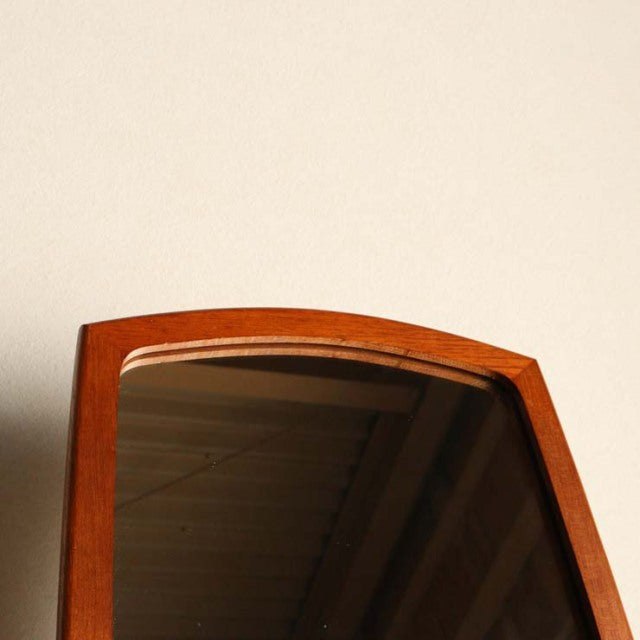 Mid-century British vintage teak mirror with arched top and smooth wood grain frame against cream wall.