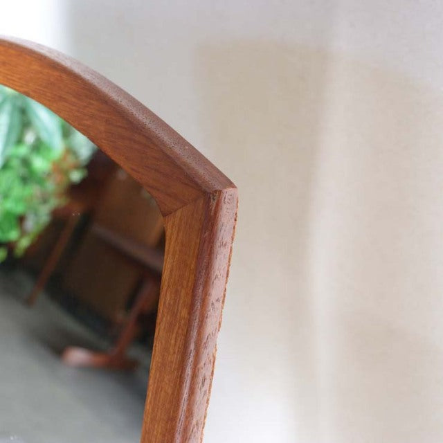 Mid-century British vintage teak mirror with curved top edge, smooth wood grain, and polished finish.