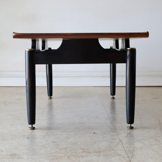 Mid-century British G-Plan teak coffee table with black tapered legs, brass feet, and sleek wood grain top.