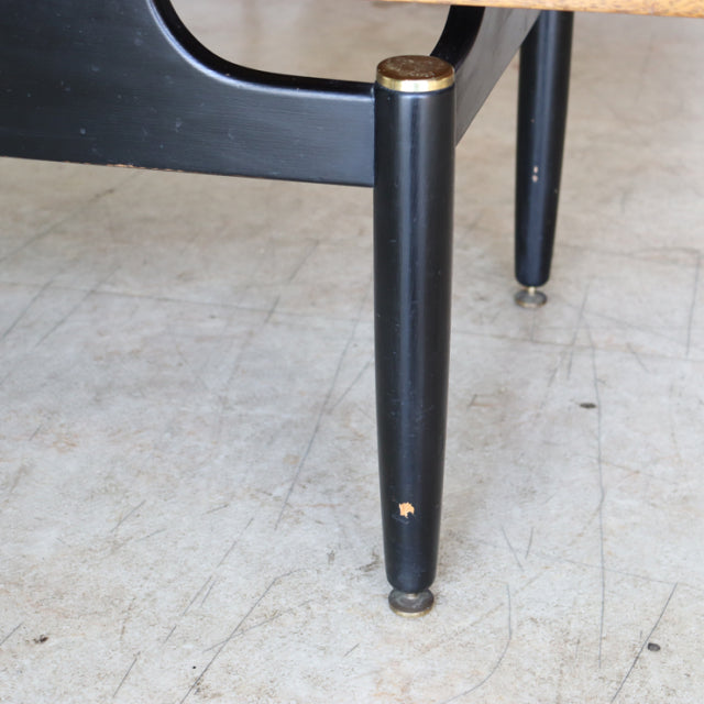 Mid-century British G-Plan coffee table leg in black with brass cap, showing teak wood grain peeking through chip damage on.