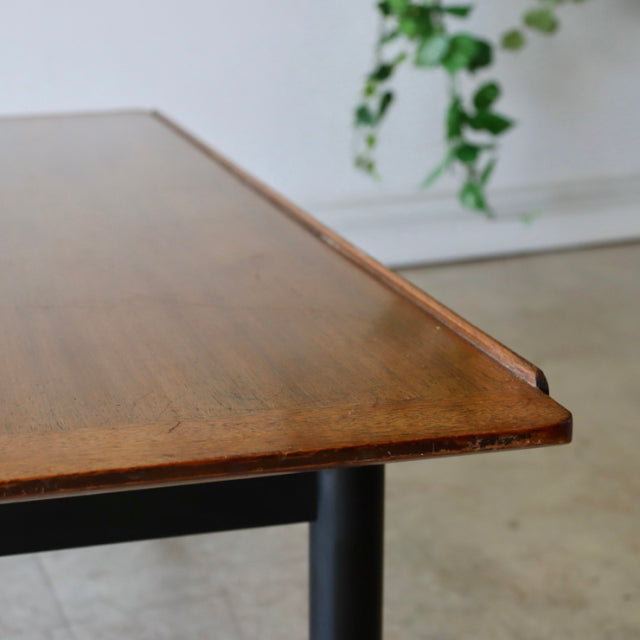 Mid-century British G-Plan teak coffee table with sleek black cylindrical legs and rich wood grain finish, vintage Danish.