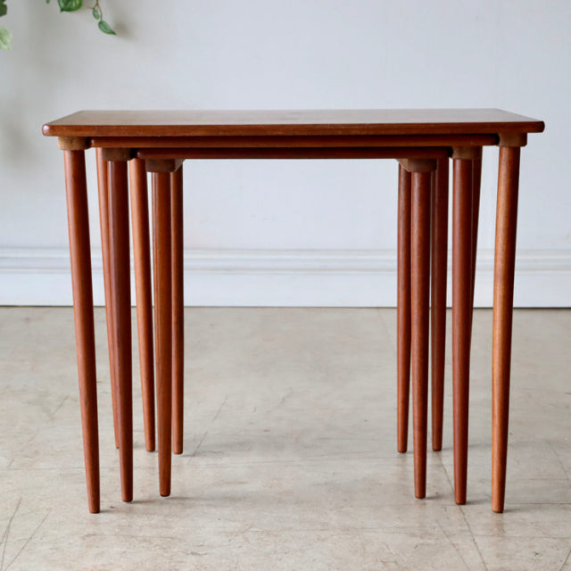 Set of three nested vintage teak tables with slender tapered legs, showcasing mid-century Danish design and smooth wood.