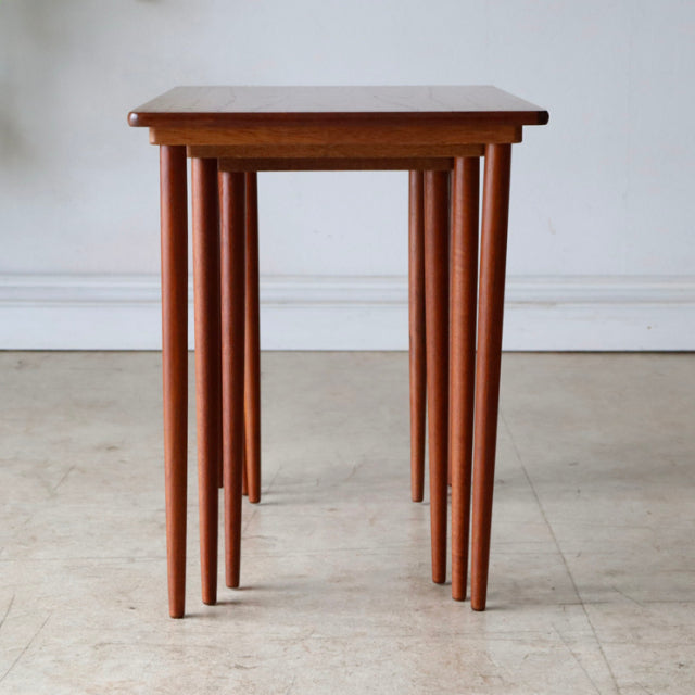 Set of vintage mid-century Danish teak nest tables with smooth wood grain and slender tapered legs in British Scandinavian.