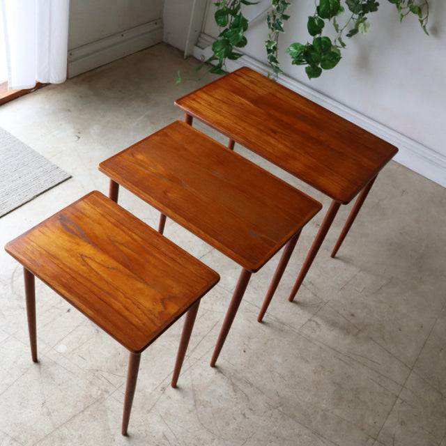 Set of three vintage teak nesting tables from mid-century Denmark with tapered legs and rich wood grain.