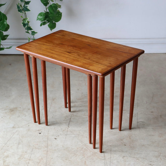 Vintage Danish mid-century teak nesting tables with smooth wood grain and slender tapered legs.