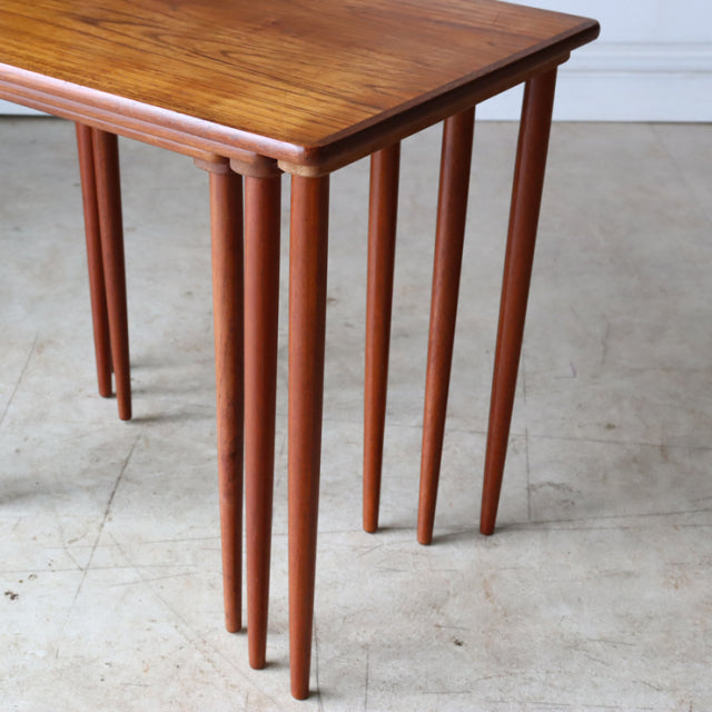 Set of three vintage mid-century Danish teak nest tables with smooth wood grain and slender tapered legs.
