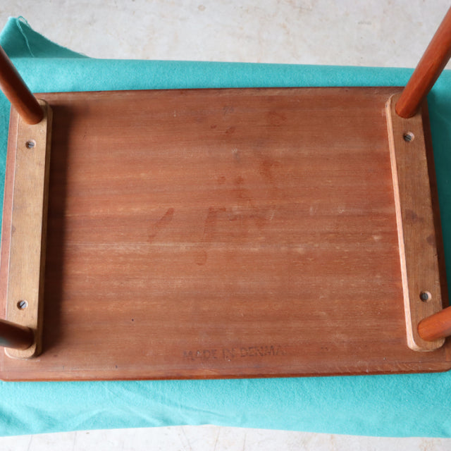 Vintage mid-century Danish teak nest table underside showing rich wood grain and sturdy wooden legs with metal fasteners.