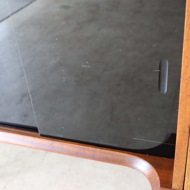 Mid-century vintage teak room divider with smooth rounded edges and dark glass panel, British design with iron legs.