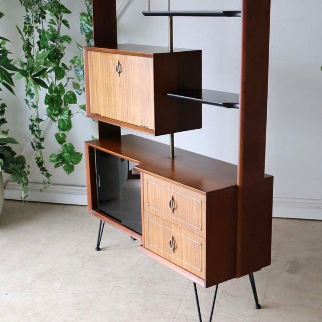 Mid-century British vintage teak room divider cabinet with iron legs, showcasing rich wood grain and textured front panels,.