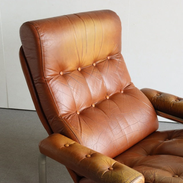 Vintage British mid-century sofa with rich teak frame and smooth brown leather tufted cushions.