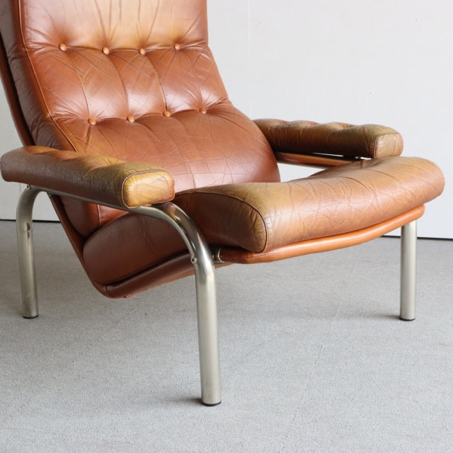 Vintage British mid-century sofa with aged teak armrests, rich brown leather upholstery, and sleek curved metal legs,.