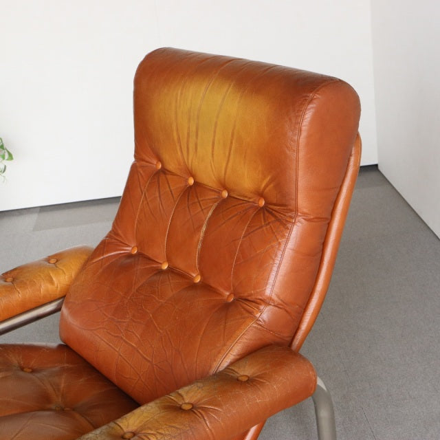 Vintage British mid-century sofa with rich teak frame, tufted aged leather upholstery, and curved armrests.