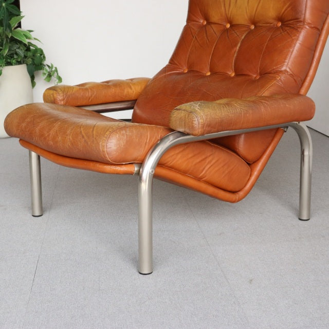 Mid-century vintage British leather lounge chair with tufted caramel upholstery and sleek brushed metal frame.