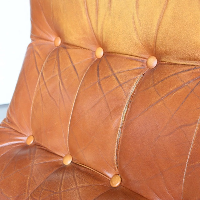 Vintage British mid-century leather sofa close-up showing rich caramel leather with button tufting and detailed stitching on .