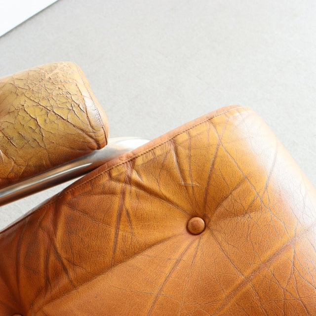 Close-up of vintage mid-century British sofa armrest in aged teak leather with visible grain and button tufting.