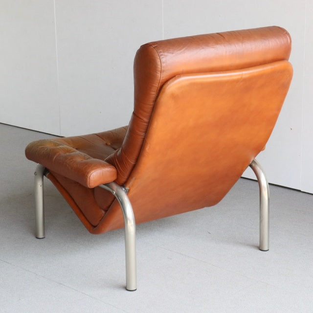 Mid-century vintage British sofa with rich teak wood grain frame and smooth caramel leather upholstery, supported by sleek.