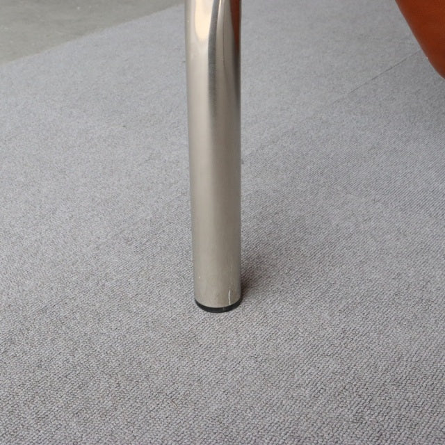 Close-up of a sleek polished metal leg on a mid-century vintage teak British sofa, showing smooth reflective surface and.