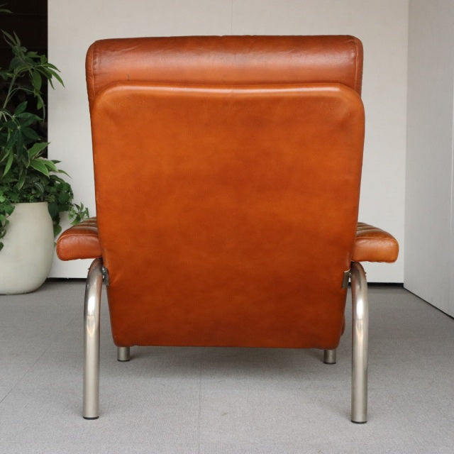 Vintage mid-century British leather sofa with smooth teak wood grain, tubular metal legs, and rich caramel patina.