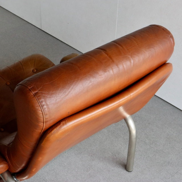 Mid-century vintage British leather sofa with smooth teak frame and curved metal legs, rich patina.