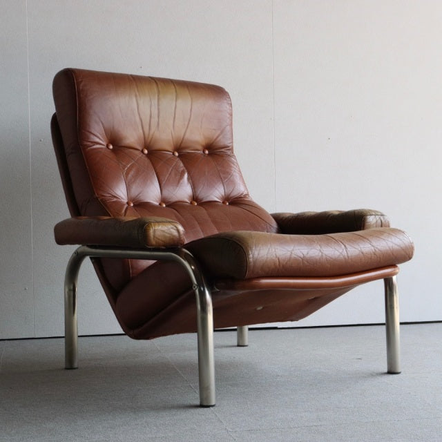 Vintage British mid-century leather lounge chair with deep button tufting, rich brown teak frame, and polished chrome legs,.
