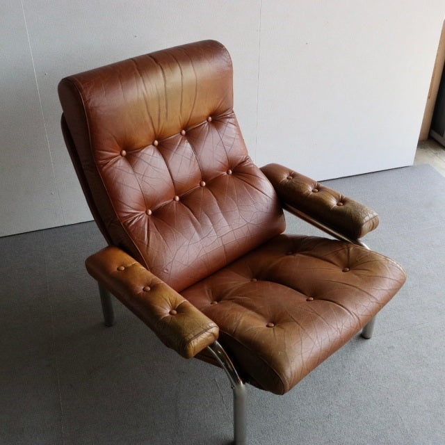Mid-century vintage British sofa with rich brown teak leather upholstery, tufted seat and backrest, wooden armrests, and.