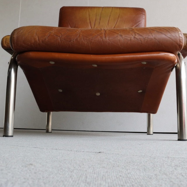 Mid-century British vintage leather sofa with rich teak wood grain, polished metal legs, and a low-profile frame.