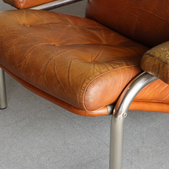 Vintage mid-century British leather sofa seat with rich teak wood frame and polished metal legs showing natural wood grain.