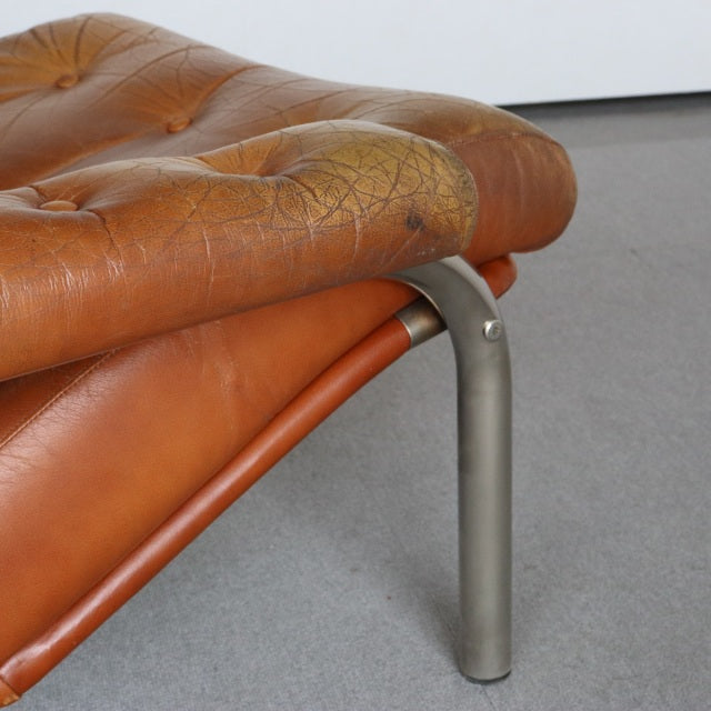 Close-up of vintage mid-century British leather sofa corner showing aged teak leather cushion with textured patina and.