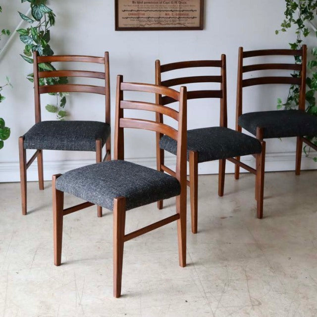 Set of four vintage mid-century teak dining chairs with dark upholstered seats, British design with sleek ladder-back and.