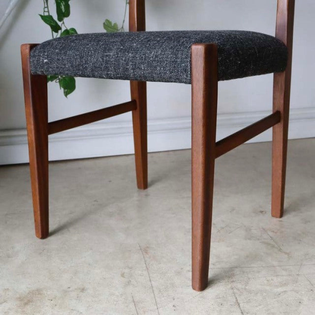 Set of four vintage teak dining chairs with mid-century British design, dark textured fabric seats, clean wood grain, and.