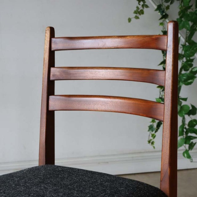 Vintage teak dining chair with curved ladder back, mid-century British design, smooth wood grain, sturdy legs, dark.