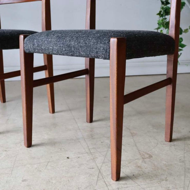 Set of four vintage teak dining chairs, British mid-century design with gray upholstered seats, tapered legs, and visible.