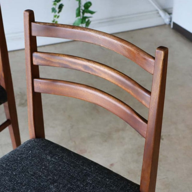 Mid-century vintage British teak dining chair with curved slat backrest and black upholstered seat cushion, showcasing rich.