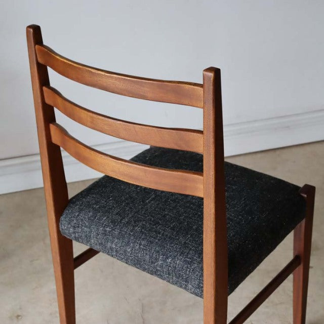 Vintage teak dining chair with mid-century British design, ladder-back frame and dark upholstered seat.