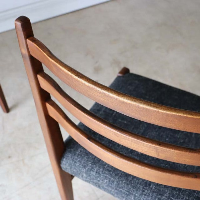 Set of four vintage teak British mid-century dining chairs with dark upholstered seats and smooth wood grain on curved.