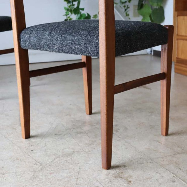 Mid-century British vintage teak dining chair with dark textured fabric seat and tapered legs.
