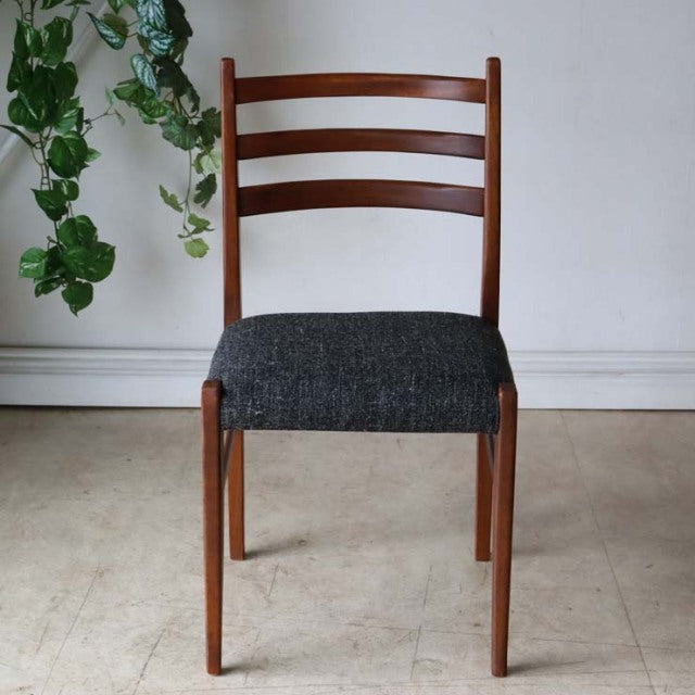 Vintage teak mid-century British dining chair with dark grey upholstered seat and ladder back design.