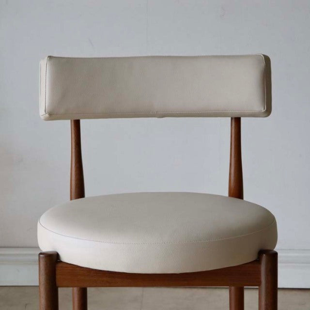 Mid-century British vintage teak dining chair with round cream leather seat and rectangular cushioned backrest.