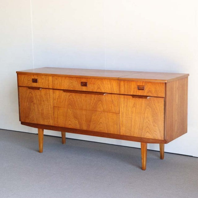 Mid-century British vintage teak sideboard with rich wood grain, three drawers, and tapered legs from Denmark design.