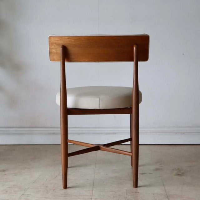 Set of two vintage G-plan mid-century teak dining chairs with cream upholstered seats, sleek wood grain and tapered legs.