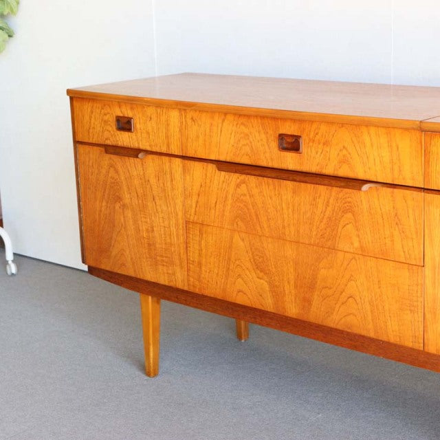 Mid-century British vintage teak sideboard with rich wood grain and tapered legs, Danish design influences visible in clean.