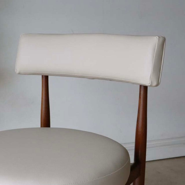 Set of two British vintage G-plan dining chairs in mid-century teak with beige rounded cushioned seats and curved backrests.