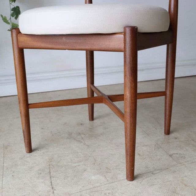Mid-century British vintage teak dining chair with tapered round legs and white cushioned seat, clean lines and visible wood .