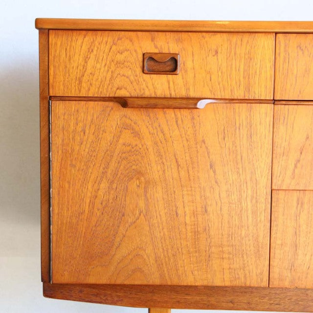 Mid-century British vintage teak sideboard with rich wood grain, recessed handles, and tapered legs from Denmark style.