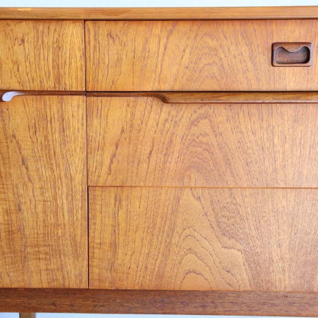 Close-up of vintage British mid-century teak sideboard showing rich wood grain, smooth drawer fronts, and rounded recessed.